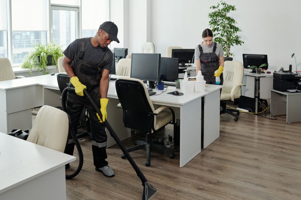 Workers of cleaning service company carrying out their work in openspace office